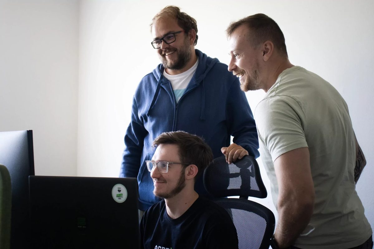 Mladší kolega u monitoru se dvěma zkušenějšími kolegy